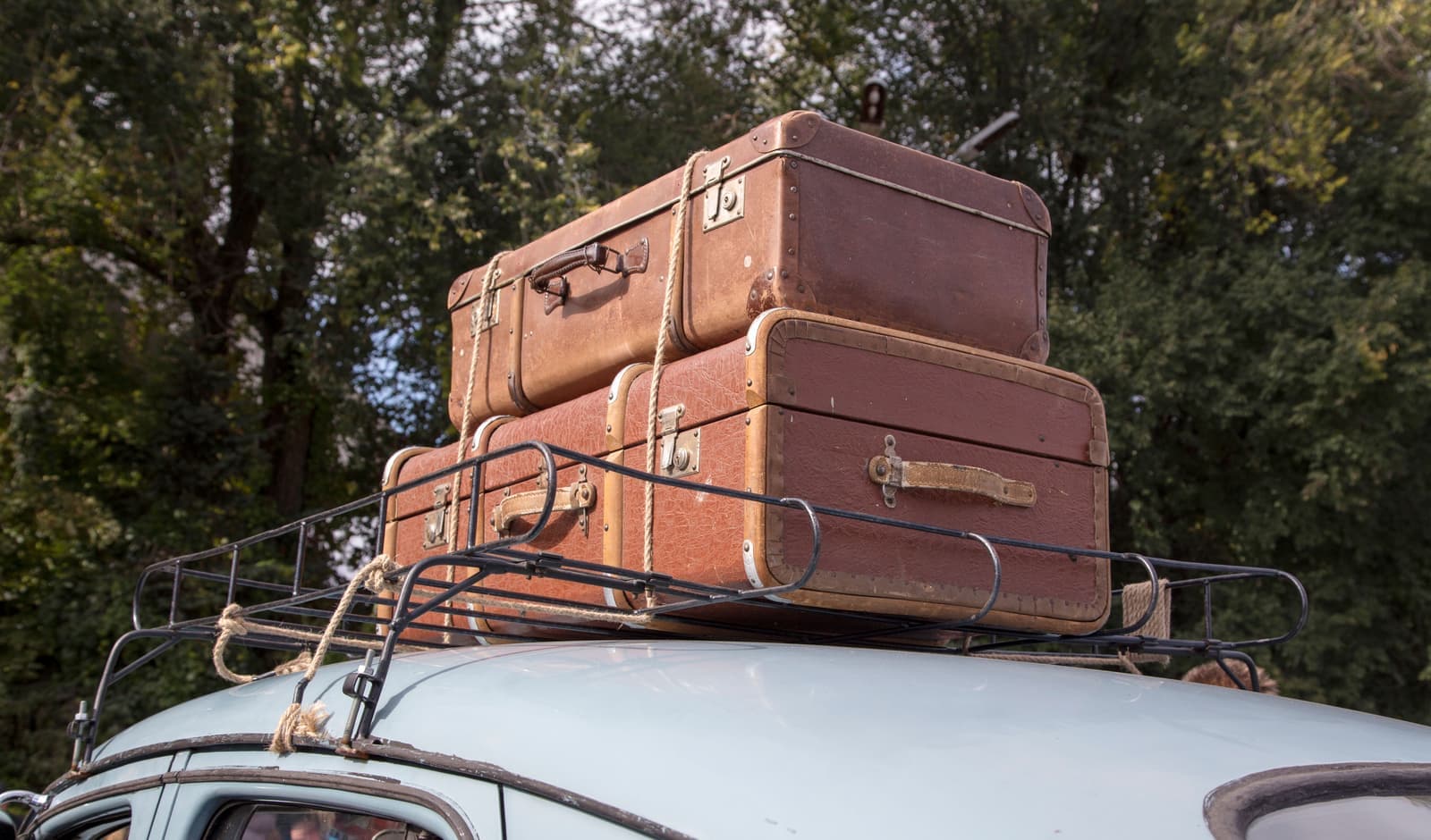 A car loaded with luggage on its roof rack, parked on a mountain road at the start of a trip