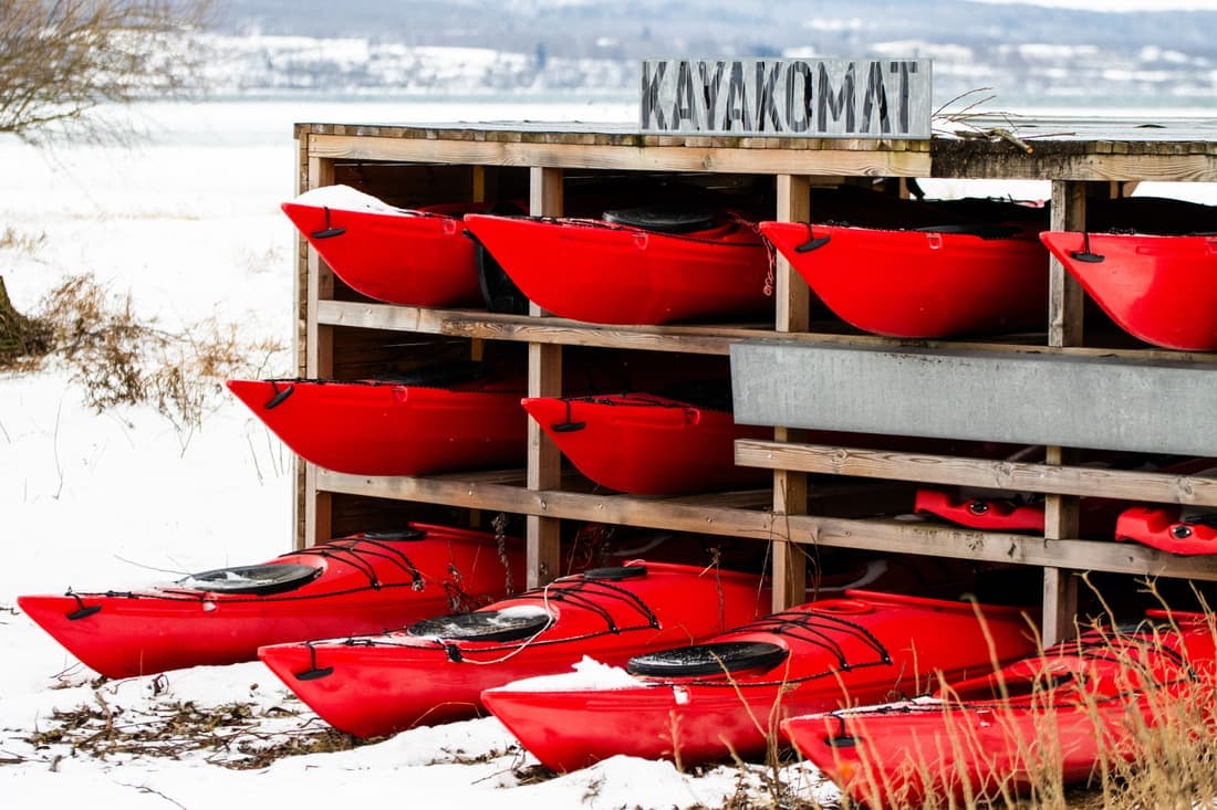 Kayaks strapped to the roof rack of a car beside a lake